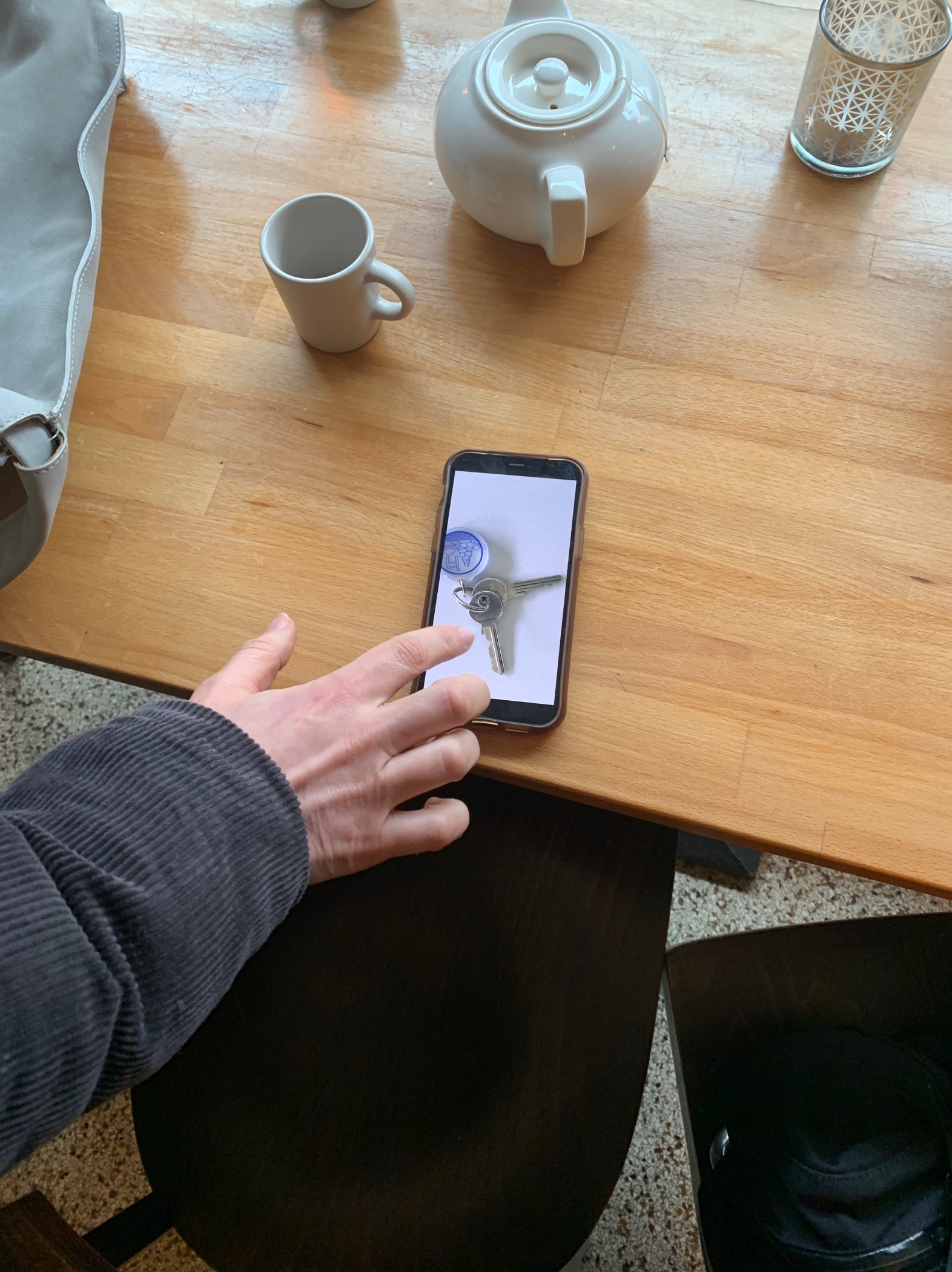 a hand reaching out to a iPhone with a photo of a key displayed on it